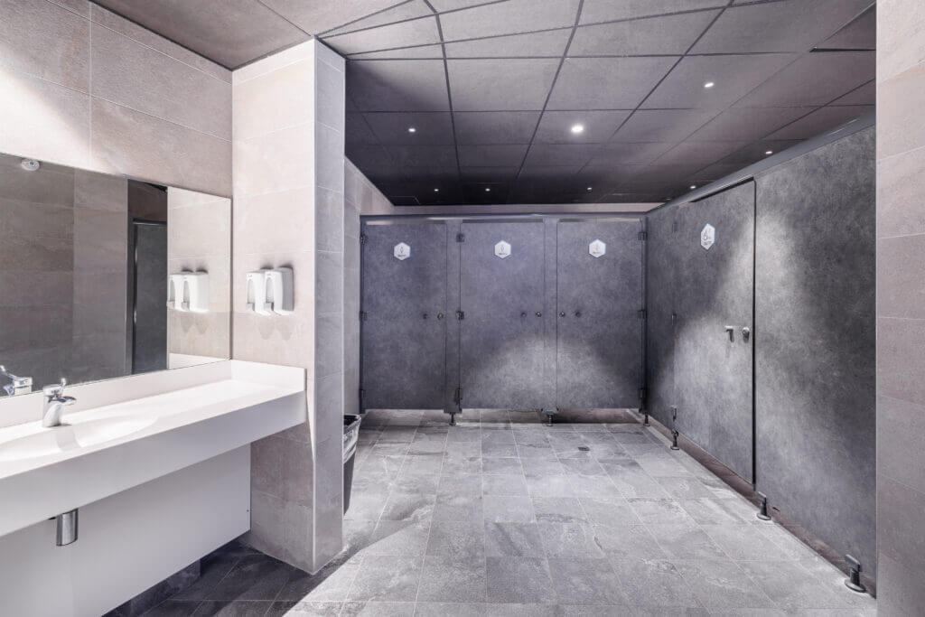 Sanitaires de l’Aquascope : cabines en stratifié compact gris et plan vasque blanc