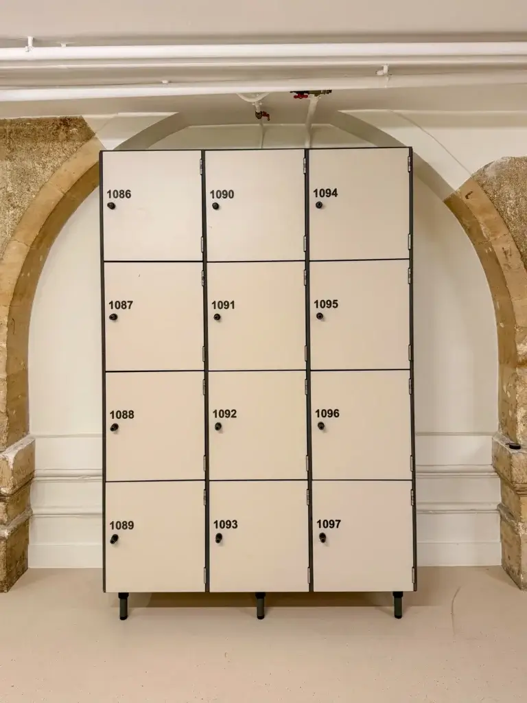Bloc de douze casiers de rangement numérotés de 1086 à 1097, sur pieds, placé sous un arc en pierre