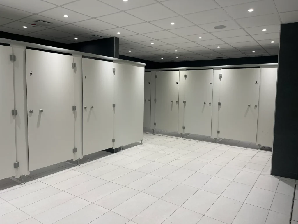 Cabines de douche et cabines sanitaires blanches en stratifié compact, dont une signalée pour les personnes à mobilité réduite