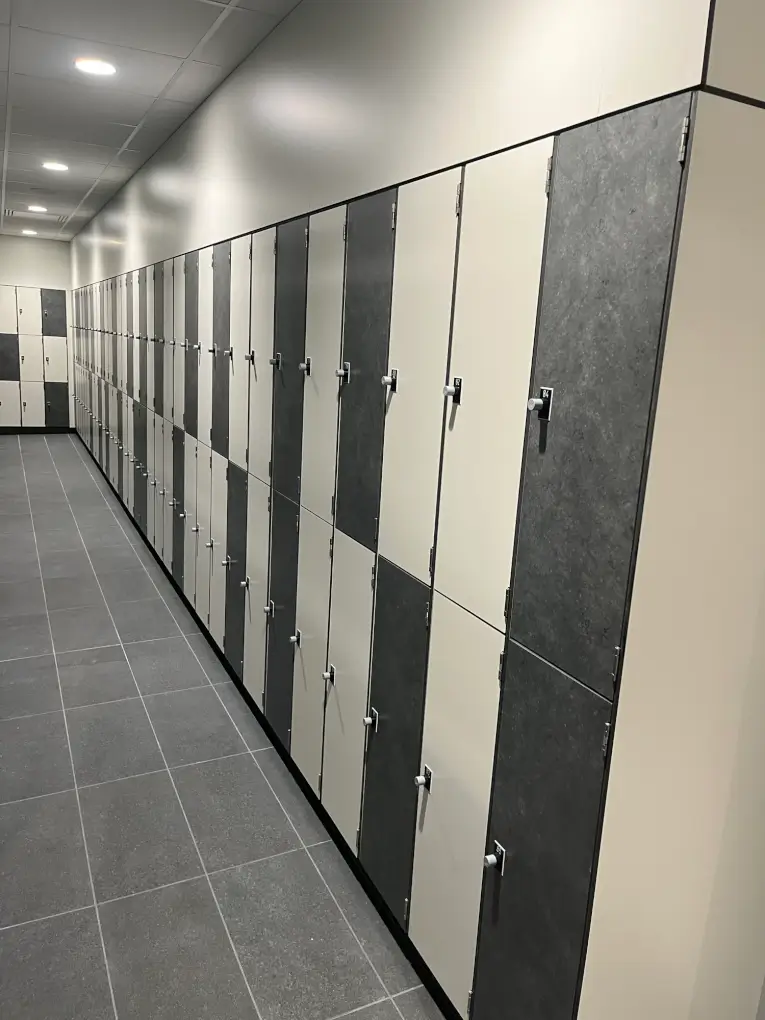 Longue rangée de casiers à portes gris minéral et ton clair, surmontée d'un habillage jusqu'au plafond, au centre Aquavithal