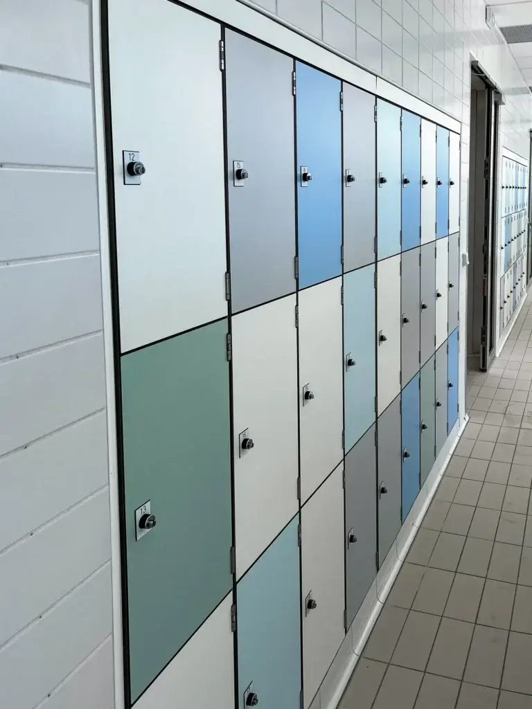 Casiers sur trois hauteurs encastrés dans une alcôve carrelée, entourés d'un fileur blanc, avec plaquettes numérotées