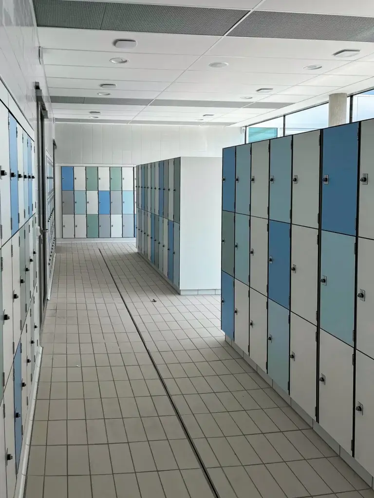 Vestiaire du centre aquatique de Valognes : îlots de casiers sur deux et trois hauteurs, et casiers encastrés au fond