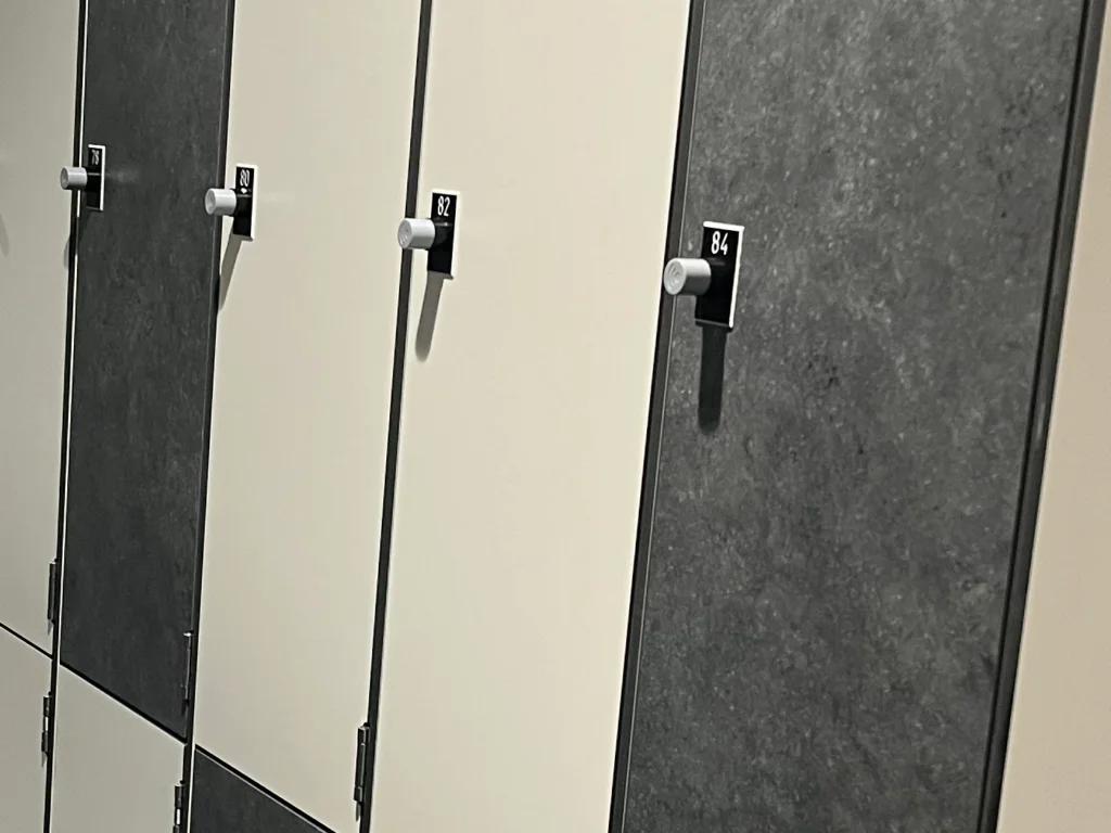 Détail de portes de casiers : serrures électroniques à bouton et plaquettes numérotées 80, 82 et 84