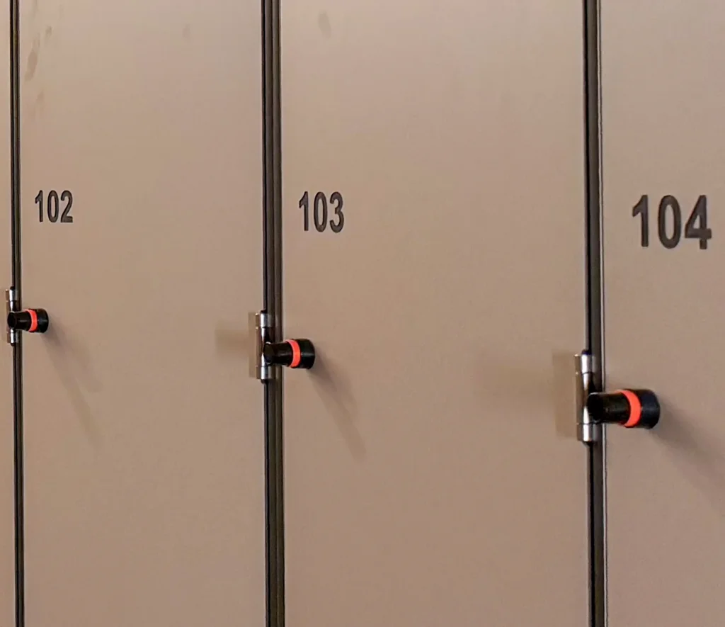 Gros plan sur trois portes de casiers numérotées 102, 103 et 104, avec le bouton de la serrure électronique