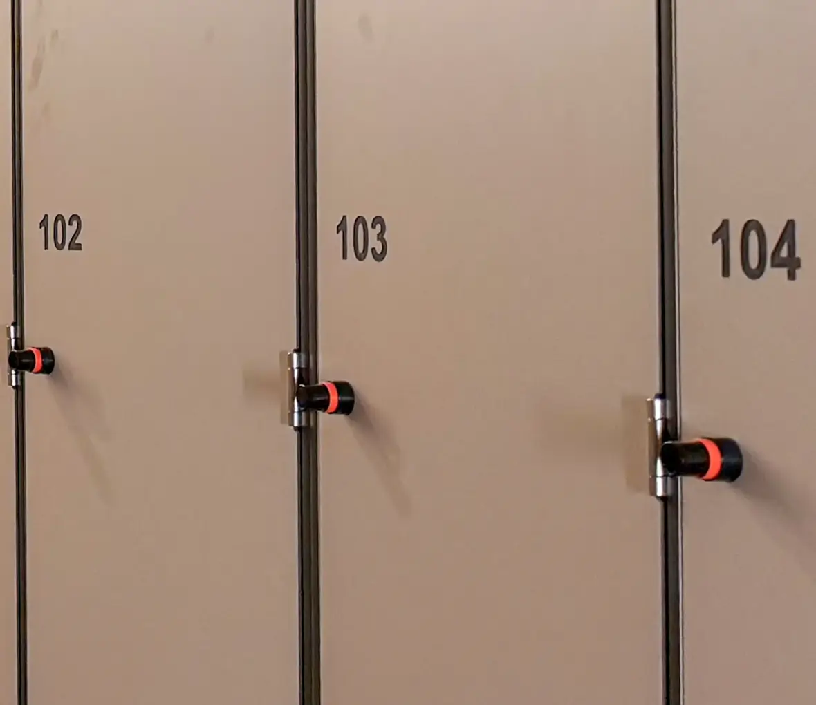 Gros plan sur trois portes de casiers numérotées 102, 103 et 104, avec le bouton de la serrure électronique