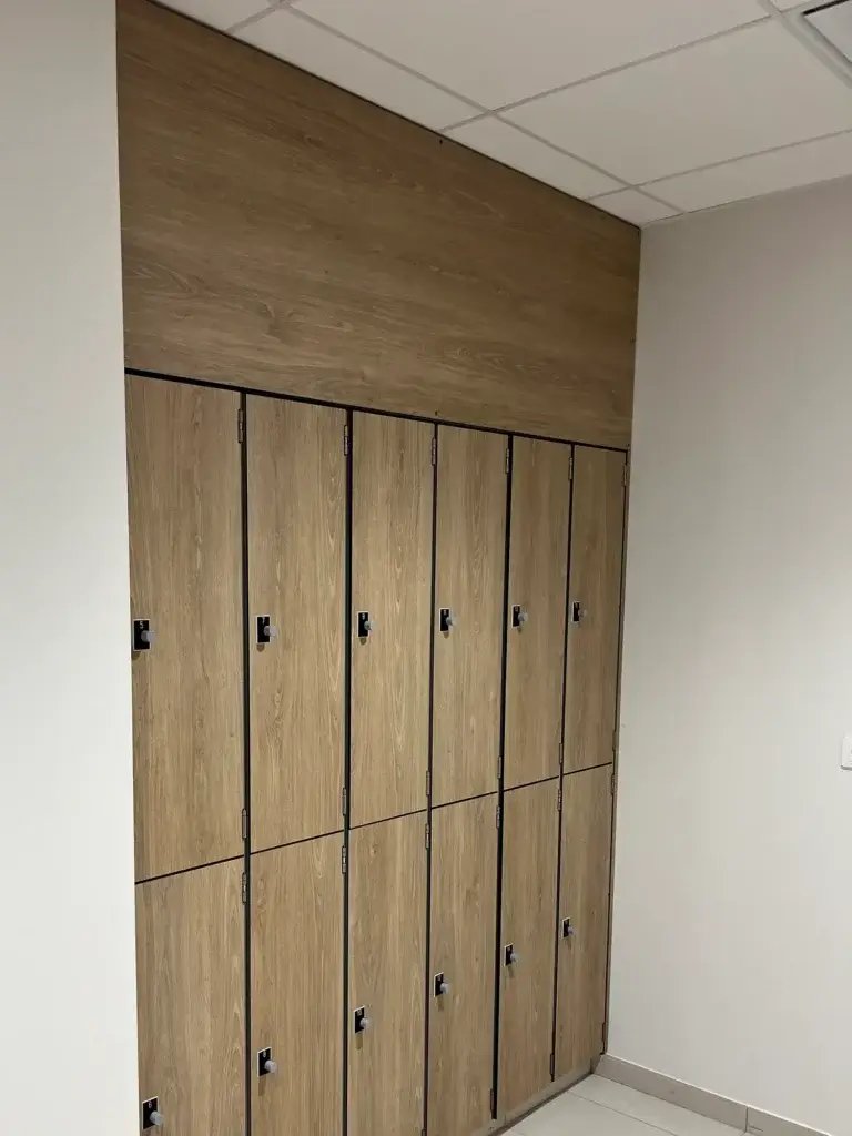 Casiers en décor chêne encastrés entre deux murs, avec une imposte du même décor jusqu'au plafond