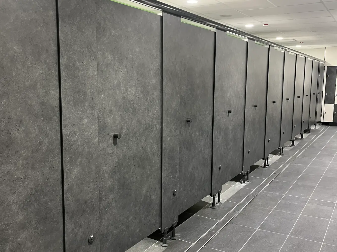 Rangée de cabines de déshabillage en stratifié compact gris minéral, montées sur pieds, au centre Aquavithal