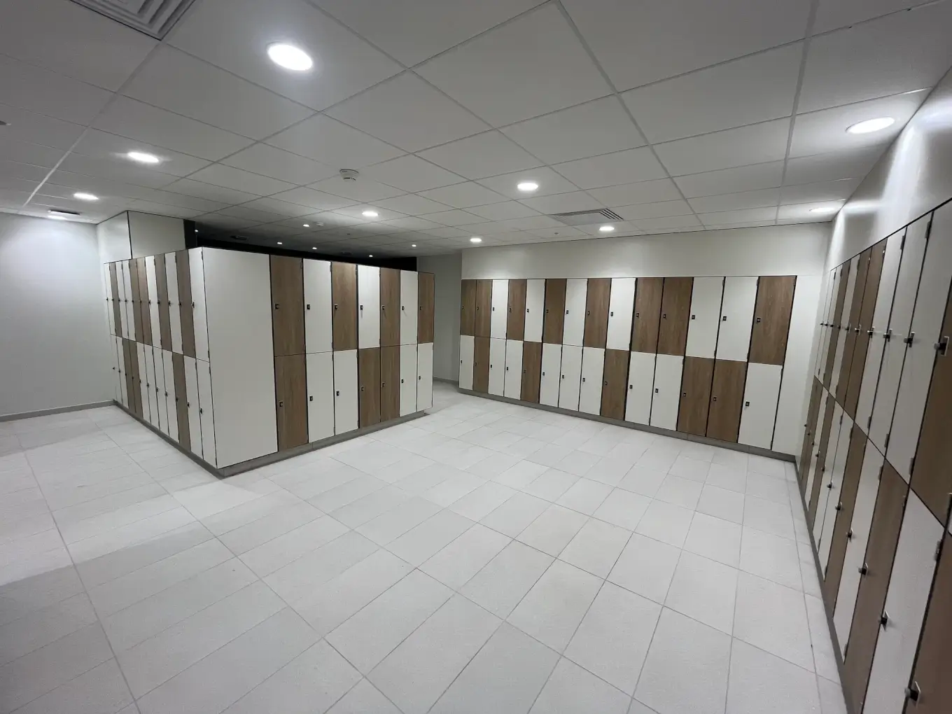 Vestiaire de l'étage du centre Aquavithal : casiers à portes blanches et chêne le long des murs et en îlot central