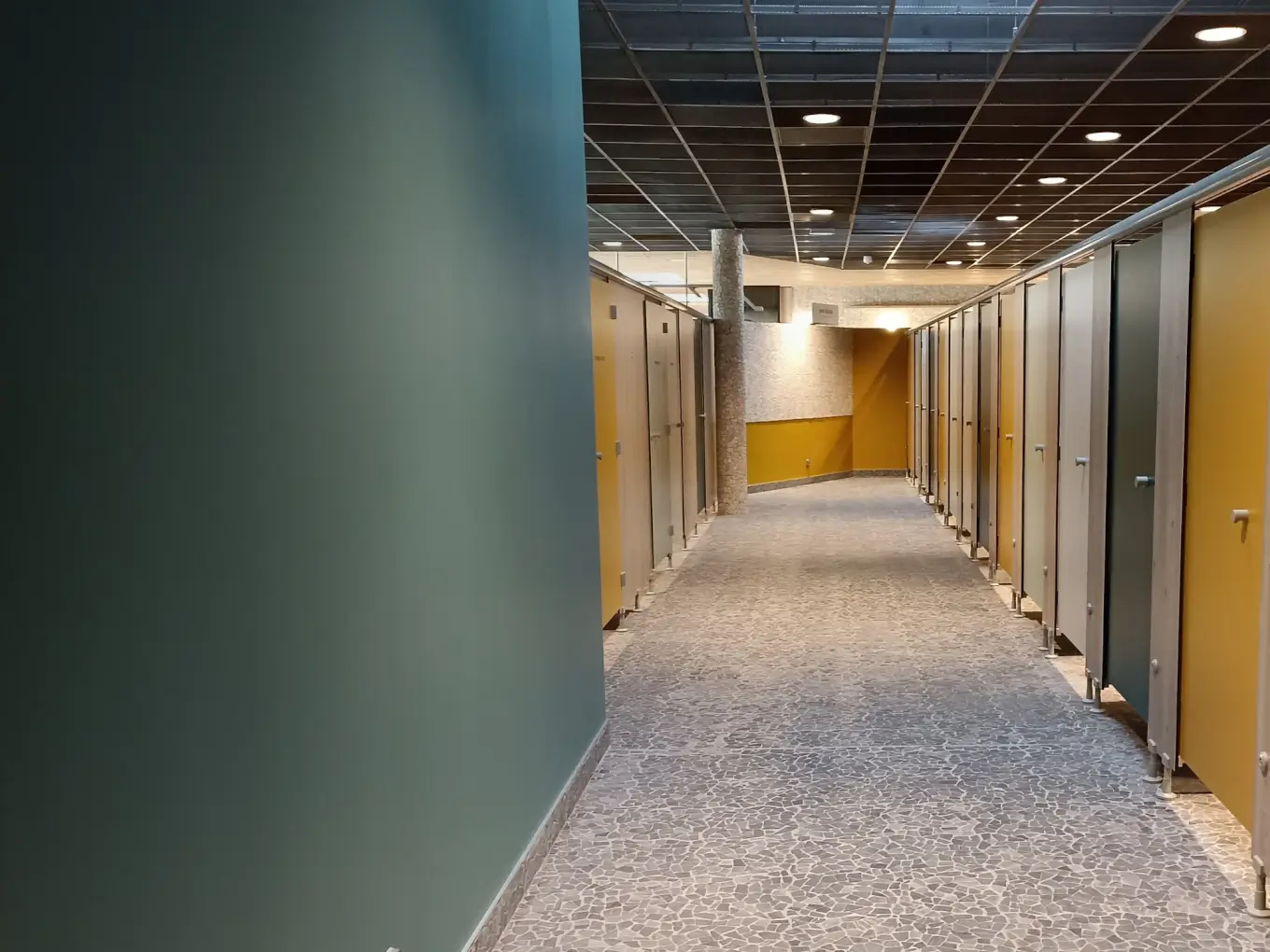 Allée de cabines de change à portes jaunes, vertes et blanches, dans les vestiaires de l'Aqua Mundo du Center Parcs Landes de Gascogne