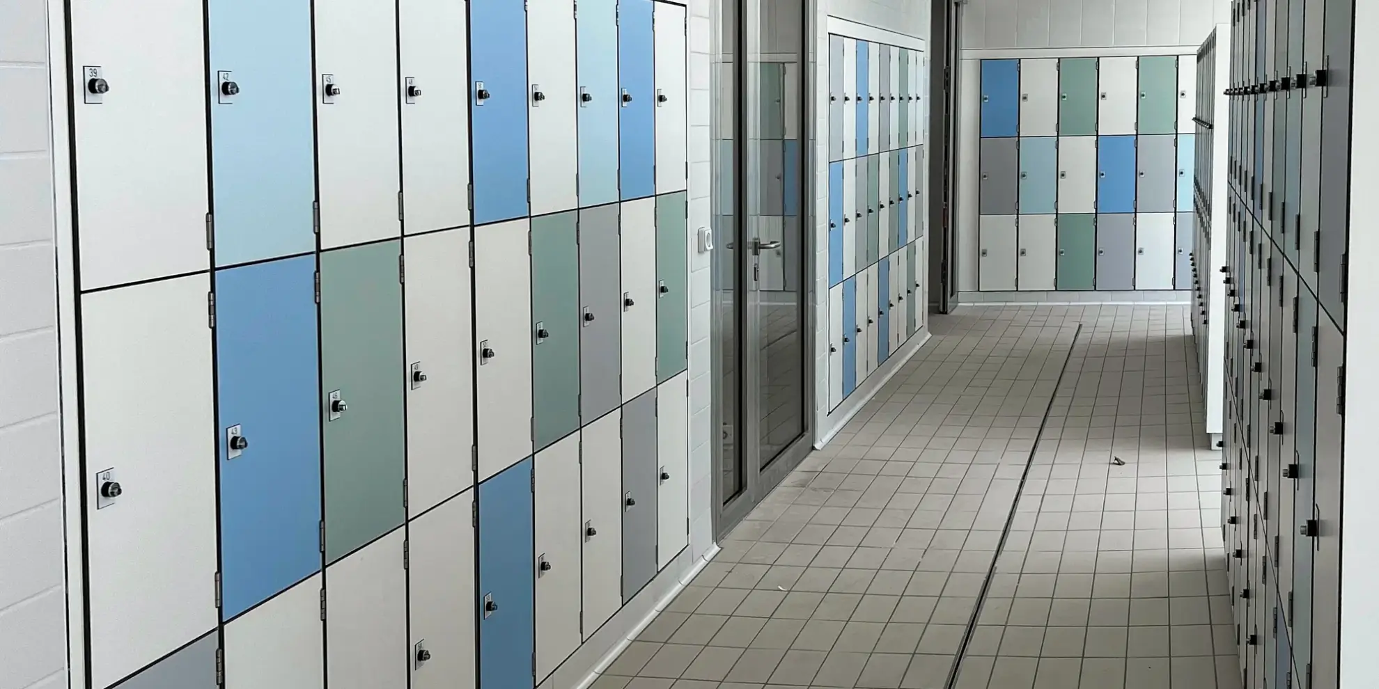 Casiers en stratifié compact encastrés dans les alcôves carrelées du vestiaire, au centre aquatique de Valognes
